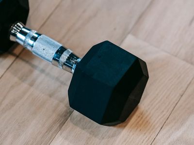 A simple dumbbell resting on a wooden floor.