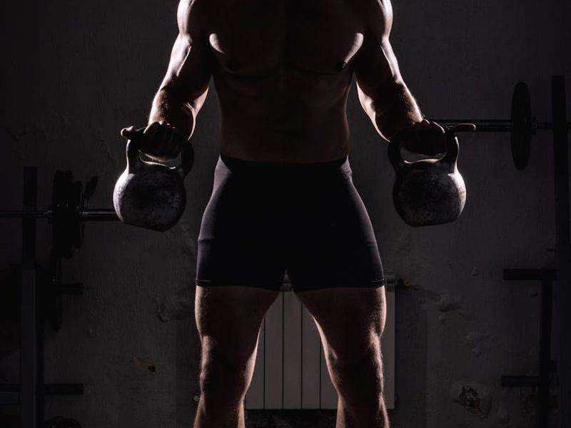 Man focused during a strength exercise in a dark gym.